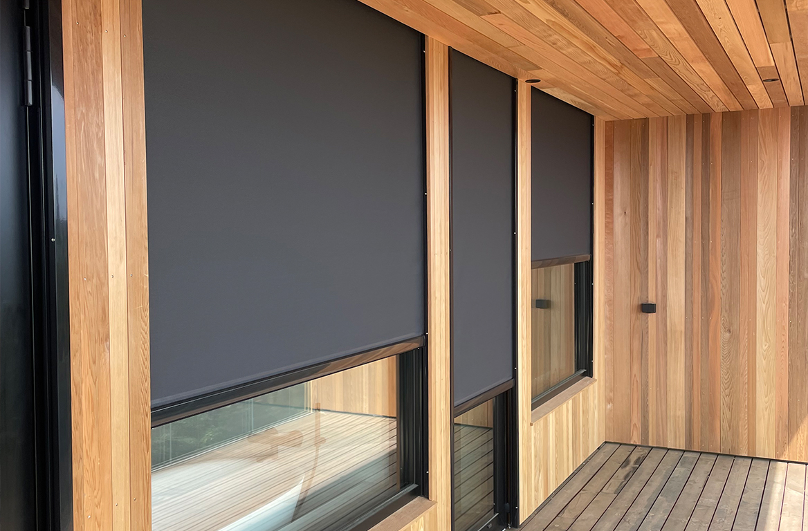 Utvendige screen-gardiner helt senket foran vinduene på en moderne trefasade.