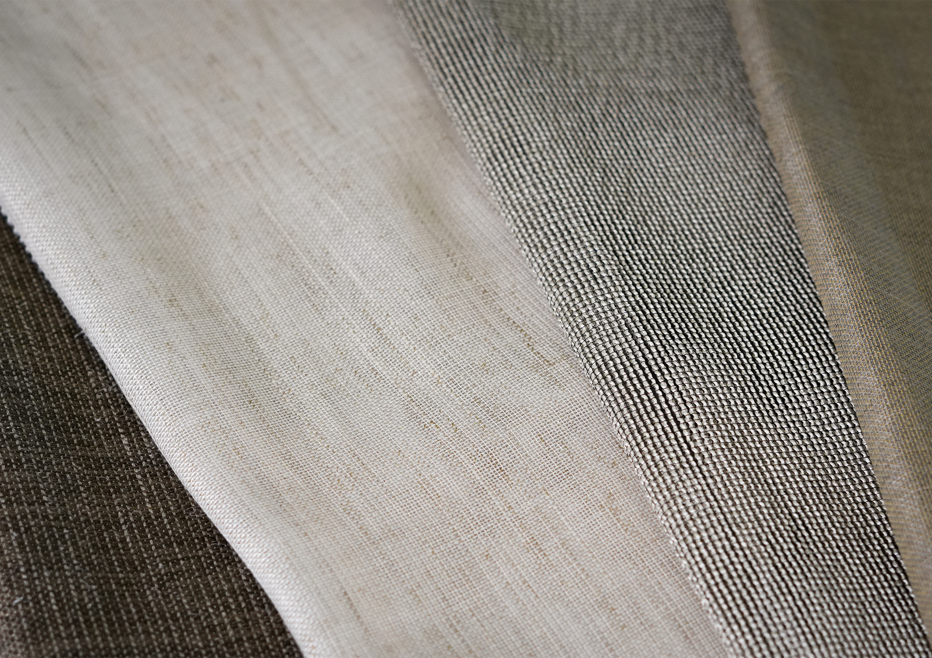 Nærbilde av nøytrale tekstilprøver i lagdelte teksturer og nyanser av beige, brunt og grått.
