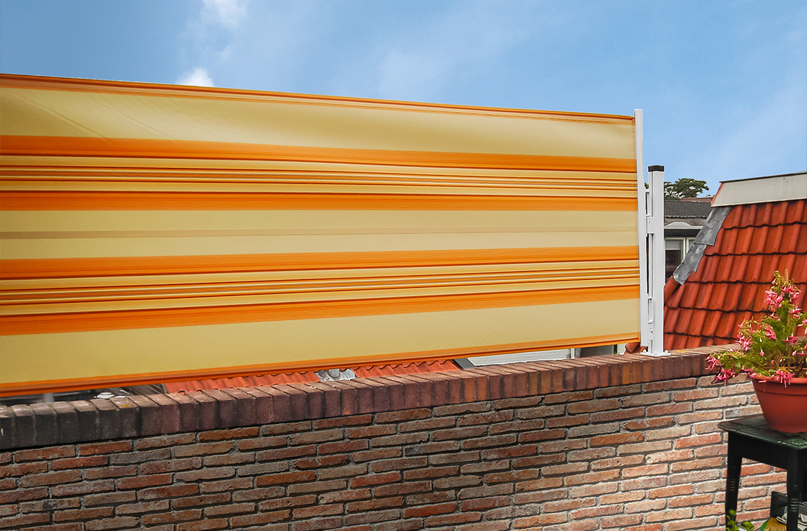 Gul- og oransjestripet levegg montert på en murvegg, med rødt tegltak i bakgrunnen.