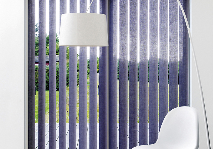 Moderne interiør med gulv-til-tak-vinduer, lilla vertikale persienner, hvit stol og gulvlampe.