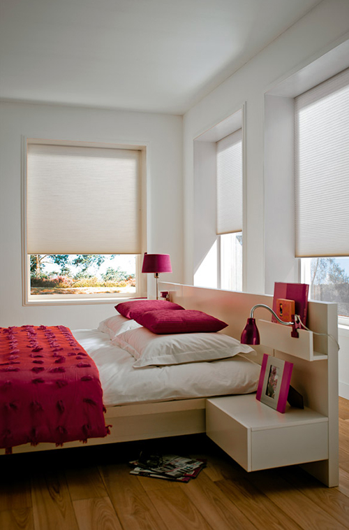Moderne soverom med hvite Duette®-gardiner, hvite vegger og magentafargede detaljer på seng og lamper.