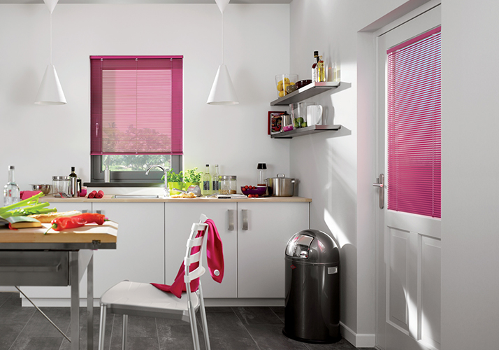 Lys, moderne kjøkken med rosa gardiner på vindu og dør, hvite skap og minimalistisk interiør.