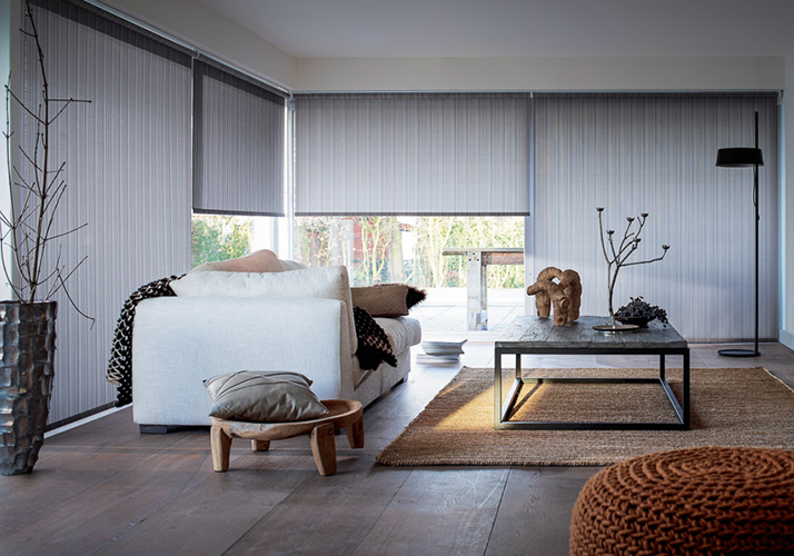 Moderne stue med grå gardiner, nøytralt møblement, detaljer i tre og en lun, samtidsinspirert stil.